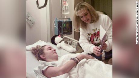 Missy Jenkins looks at a get-well card with her twin sister on Dec. 10, 1997. 