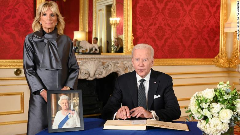 President Joe Biden, accompanied by first lady Jill Biden, signs a condolence book at Lancaster House in London.