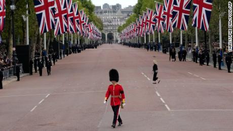A King&#39;s Guard soldier crosses The Mall outside Buckingham Palace before the funeral begins.