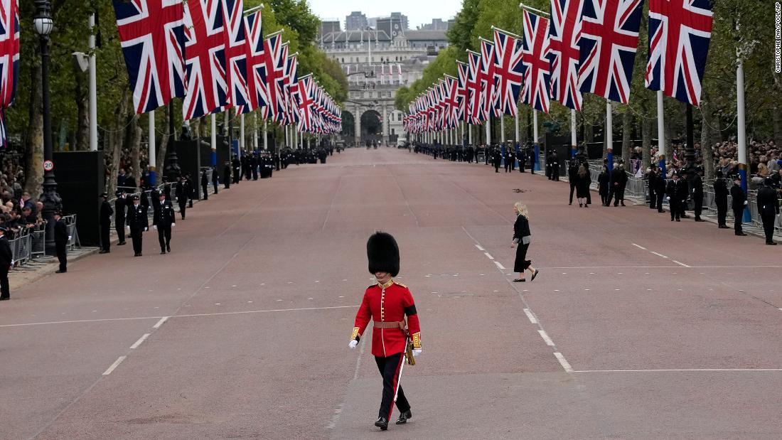 A King&#39;s Guard soldier crosses The Mall outside Buckingham Palace before the Queen&#39;s funeral procession.