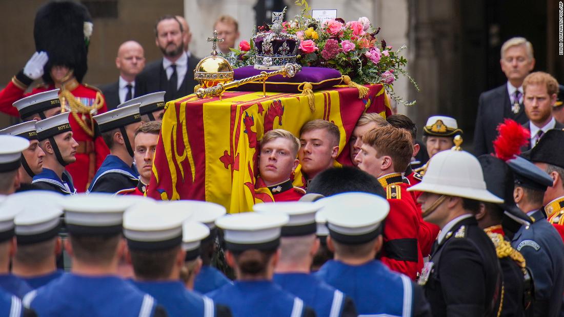 The coffin is carried into Westminster Abbey after a short procession from Westminster Hall, where the Queen was lying in state. The coffin was draped with the Royal Standard, and the Instruments of State -- the Imperial State Crown and regalia -- &lt;a href=&quot;https://www.cnn.com/uk/live-news/funeral-queen-elizabeth-intl-gbr/h_62df63a1713d7b8828a217117d826d9c&quot; target=&quot;_blank&quot;&gt;were laid upon it&lt;/a&gt; along with a flower wreath.