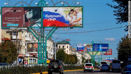 Vehicles drive past advertising boards, including panels displaying pro-Russian slogans, in Luhansk, Ukraine, on September 20.