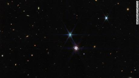 Nesta foto por Webb & # 39;  s Near-Infrared Camera, um pequeno grupo de centenas de galáxias de fundo, variando em tamanho e forma, aparece ao lado de Netuno.