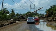 Cars drive under a downed utility pole in the aftermath of Hurricane Fiona in Santa Isabel, Puerto Rico, Wednesday.