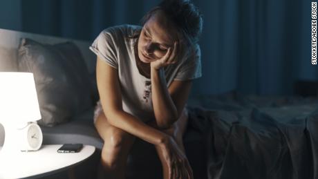 Exhausted woman suffering from insomnia, she is sitting on the bed and thinking
