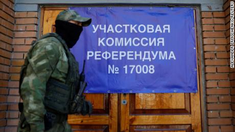 A service member of the self-proclaimed Donetsk People&#39;s Republic passes a banner at a polling station ahead of the planned referendum on September 22.