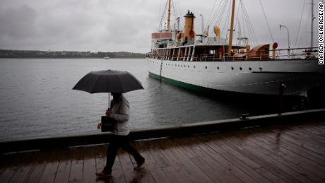 Un peatón se protege con un paraguas mientras camina por el paseo marítimo de Halifax mientras la lluvia cae antes de que el ciclón Fiona toque tierra en Halifax, el viernes 23 de septiembre de 2022.