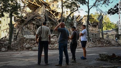 Passers-by stand near a destroyed building following an overnight missile strike in Kharkiv, on August 29, 2022, amid Russia&#39;s military invasion launched on Ukraine.