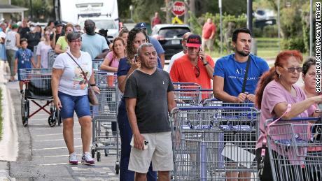İnsanlar 25 Eylül 2022'de Kissimmee, Florida'daki Tropical Storm Ian'a hazırlanmak için acele ederken, alışveriş yapanlar bir perakende deposunun önünde kuyrukta bekliyorlar. 