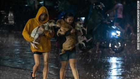 25 Eylül'de Filipinler'in Manila banliyösü Marikina kentinde şiddetli yağmur altında evcil hayvanlarını bir tahliye merkezine taşıyan sakinler.