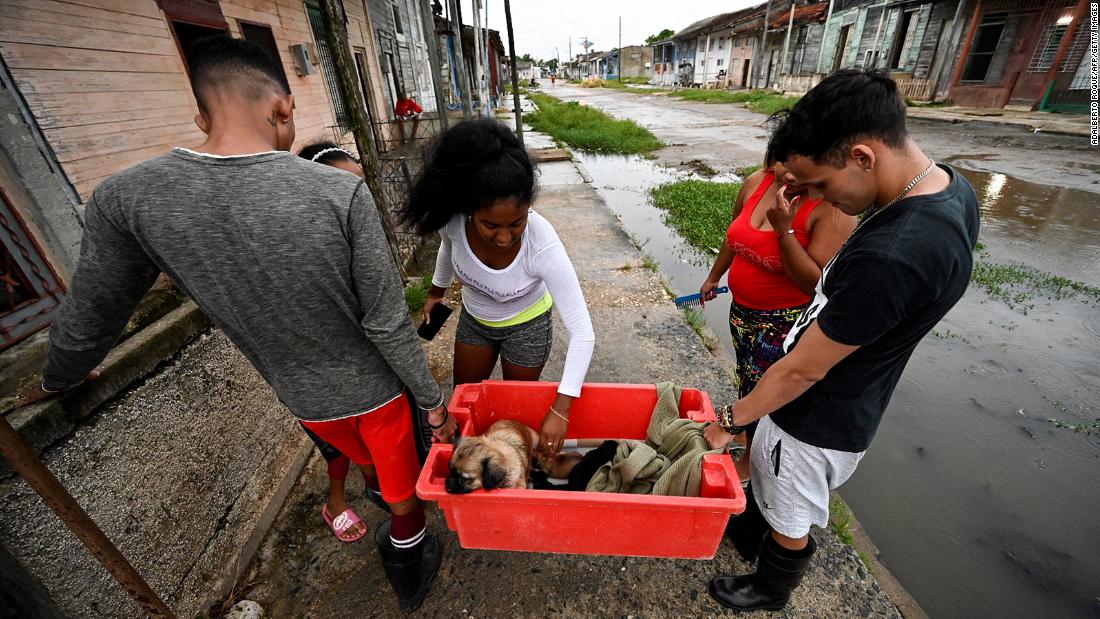 A family carries a dog to a safe place in Batabano on Monday.