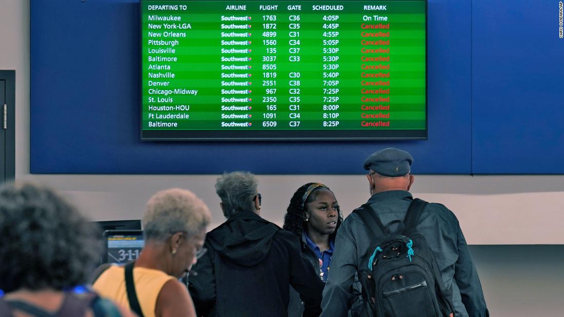 Southwest Airlines passengers check in near a sign that shows canceled flights at the Tampa International Airport on Tuesday.