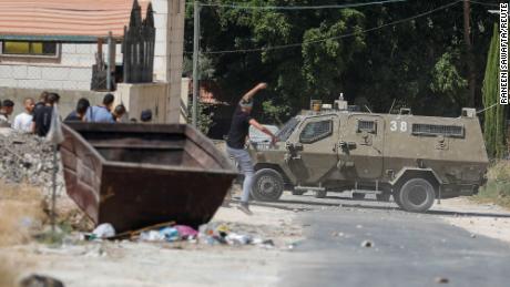 A Palestinian hurls a stone at an Israeli army vehicle during clashes in Jenin on September 28.