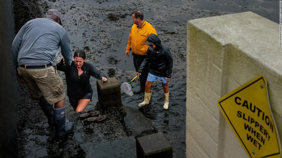 A woman is helped out of a muddy area Wednesday in Tampa, Florida, where &lt;a href=&quot;https://www.cnn.com/us/live-news/hurricane-ian-florida-updates-09-28-22/h_a3f82ffac9c07dccfd47dec0e86df9c5&quot; target=&quot;_blank&quot;&gt;water was receding&lt;/a&gt; due to a negative storm surge.