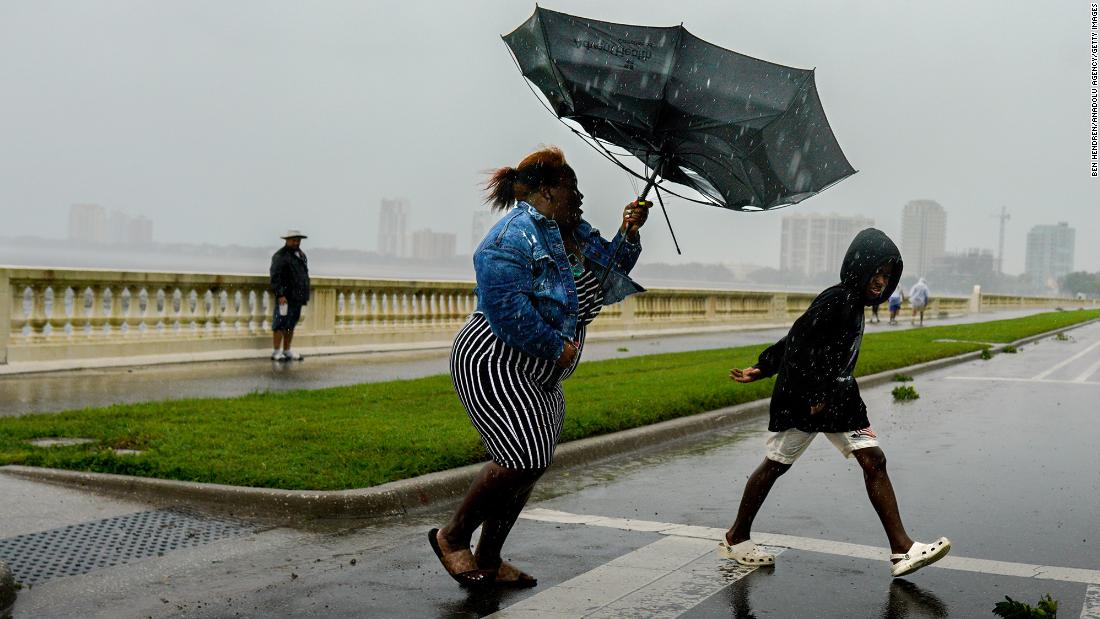 A woman holds an umbrella inverted by the wind in Tampa on Wednesday.