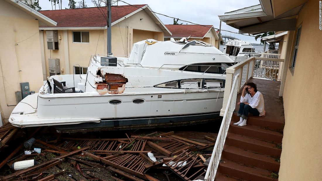 Brenda Brennan sits next to a boat that pushed up against her apartment building in Fort Myers on Thursday. She said the boat floated in around 7 p.m. Wednesday.