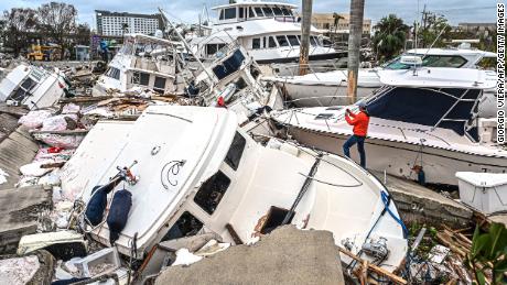 TOPSHOT - A man takes photos of boats damaged by Hurricane Ian in Fort Myers, Florida, on September 29, 2022. - Hurricane Ian left much of coastal southwest Florida in darkness early on Thursday, bringing &quot;catastrophic&quot; flooding that left officials readying a huge emergency response to a storm of rare intensity. The National Hurricane Center said the eye of the &quot;extremely dangerous&quot; hurricane made landfall just after 3:00 pm (1900 GMT) on the barrier island of Cayo Costa, west of the city of Fort Myers. (Photo by Giorgio VIERA / AFP) (Photo by GIORGIO VIERA/AFP via Getty Images)