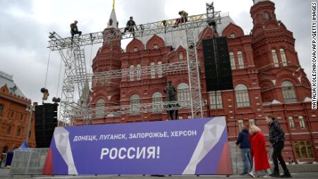 Workers fix a banner reading &quot;Donetsk, Lugansk, Zaporizhzhia, Kherson - Russia!&quot; on top of a construction installed in front of the State Historical Museum outside Red Square in central Moscow.