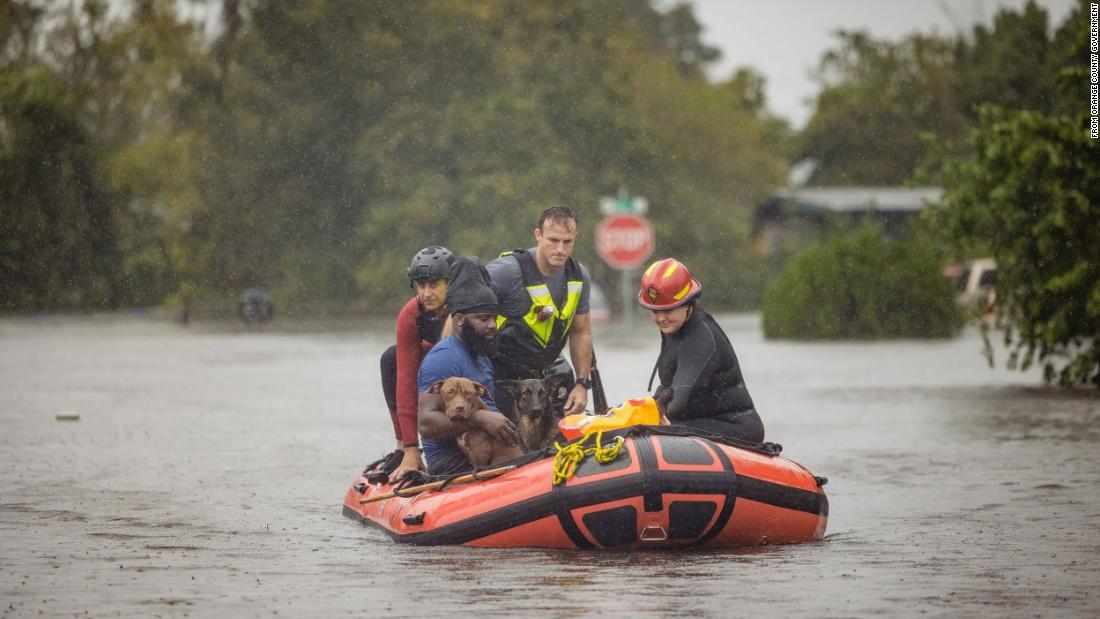 A resident of Orange County, Florida, and a couple of dogs are rescued from floodwaters on Thursday.