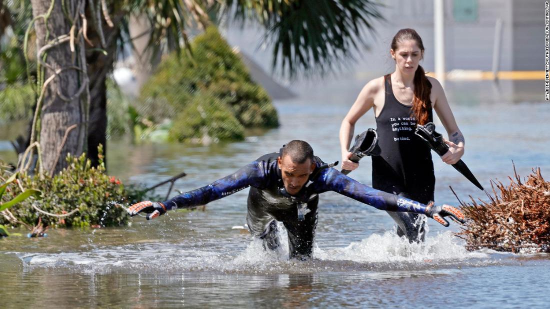 Jonathan Strong dives into floodwaters while he and his girlfriend, Kylie Dodd, knock on doors to help people in a flooded mobile home community in Iona, Florida, on Thursday. &quot;I can&#39;t just sit around while my house is intact and let other people suffer,&quot; he said. &quot;It&#39;s what we do: community helping community.&quot;