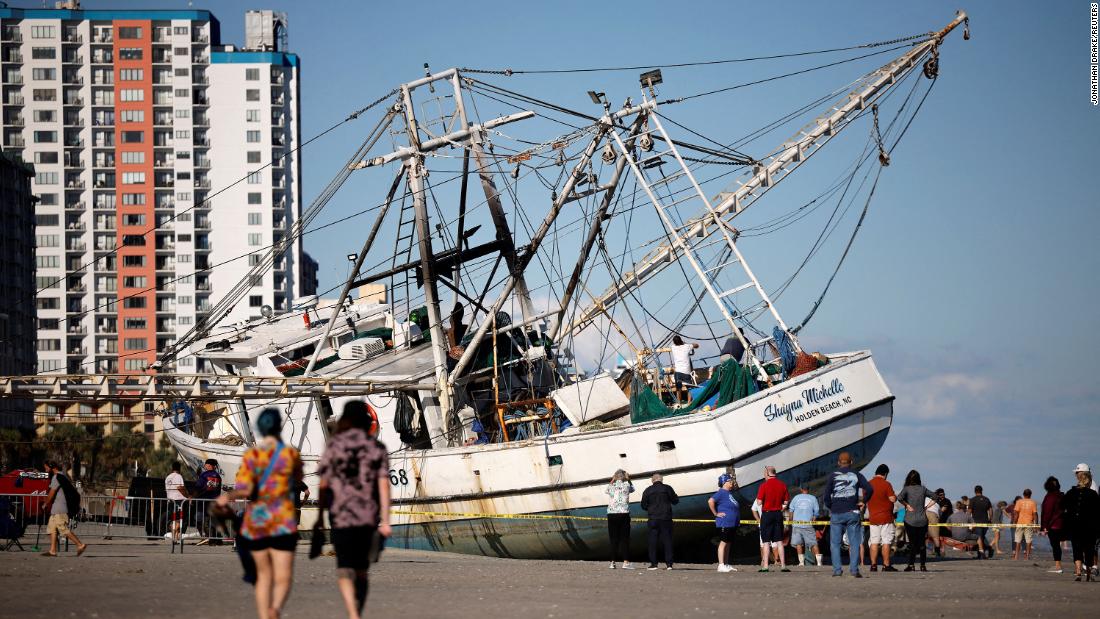 Beachgoers look at a large shrimping boat that was swept ashore in Myrtle Beach, South Carolina, on Saturday.