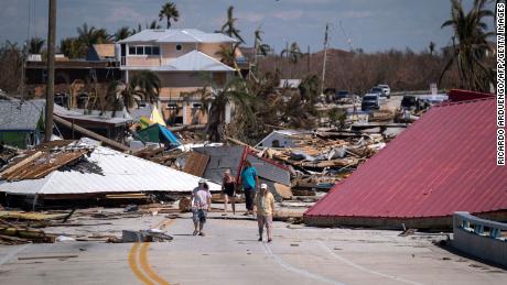 People walk pass destroyed houses and businesses in the aftermath of Hurricane Ian in Matlacha, Florida on October 1, 2022.