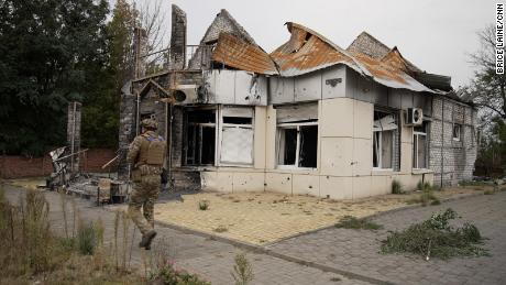 A Ukrainian soldier with the Dnipro-1 unit walks past a damaged building in central Lyman, Ukraine, on Sunday, October 2, 2022.