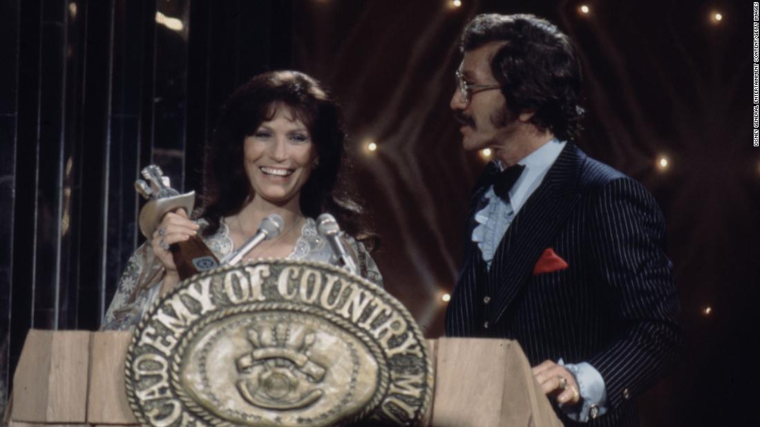 Lynn accepts the award for Entertainer of the Year from Marty Robbins at the 1976 Academy of Country Music Awards.