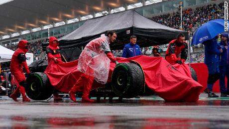 Carlos Sainz&#39;s car is carried in the pit lane during the rain delay.