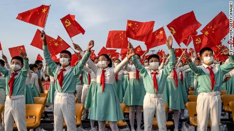 Chinese students wave party and national flags at a ceremony marking the party&#39;s centenary on July 1, 2021.