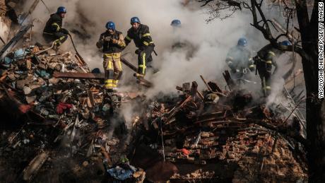 Ukrainian firefighters work on a destroyed building after a drone attack in Kyiv on October 17, 2022.