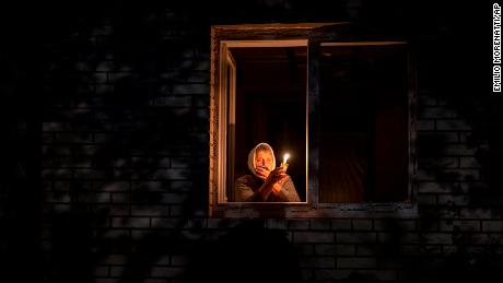 A woman looks out her window during a power outage in Borodyanka, Kyiv region, on October 20. Airstrikes cut power and water supplies to thousands of Ukrainians earlier in the week. 