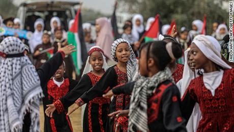 Palestinian girls wearing traditional embroidered dresses perform during a ceremony marking the start of the olive harvest season in Deir al-Balah in central Gaza on Sunday.  
