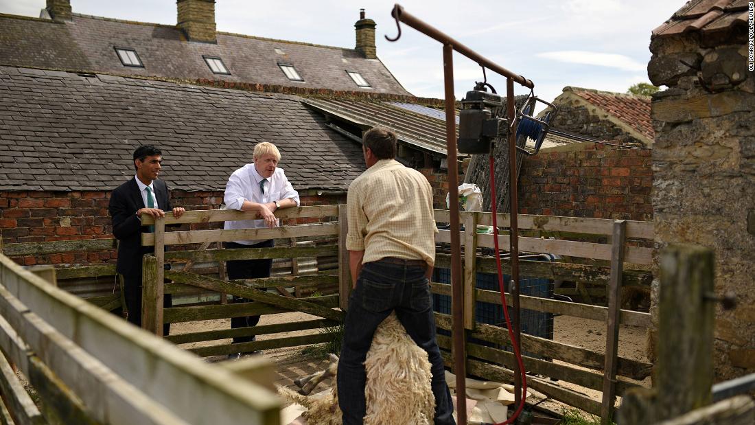 Sunak and Boris Johnson watch as a sheep is sheared during a visit to a farm in North Yorkshire, England, in July 2019. At the time Johnson was running to lead Britain&#39;s Conservative Party and Sunak was a member of Parliament.