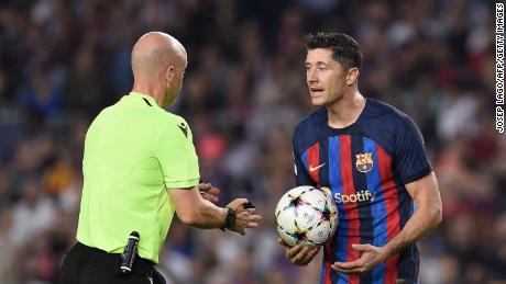 Barcelona forward Lewandowski (R) argues with English referee Anthony Taylor during the game against Bayern.