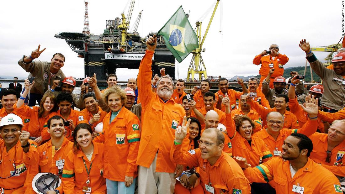 Lula waves a Brazilian flag while posing for a picture in 2008 with workers of the Brasil-Fels shipyard, who built the Petrobras oil platform in Angra dos Reis, Brazil.