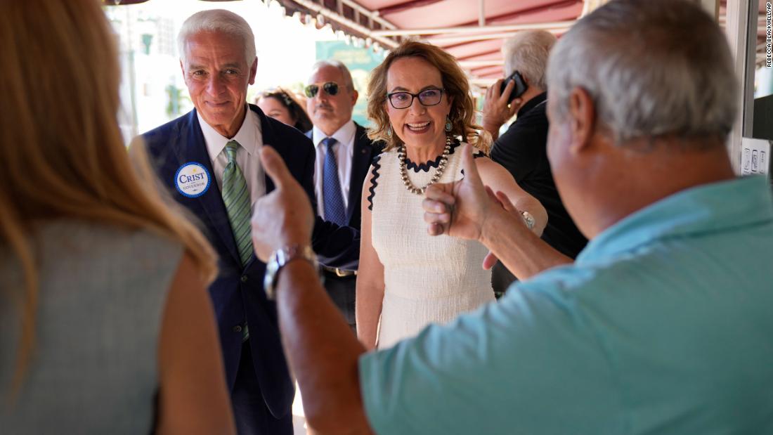 Giffords is joined by Florida gubernatorial candidate Charlie Crist, left, as they arrive at a restaurant in Miami in September 2022. State Democratic officials joined Giffords as she continued a bus tour against gun violence. 