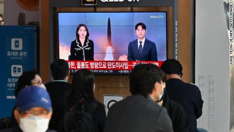 People watch a television screen showing a news broadcast with file footage of a North Korean missile test, at a railway station in Seoul on November 2, 2022.