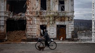 A woman rides a bicycle past a damaged building in the town of Kupiansk on November 3, 2022, Kharkiv region, amid the Russian invasion of Ukraine.