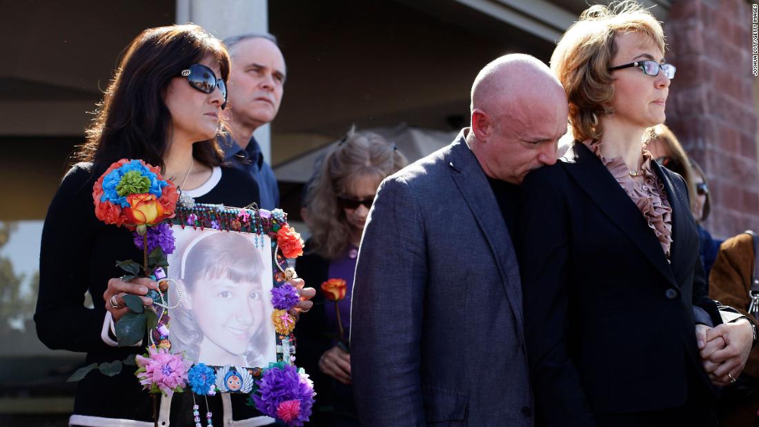 Giffords and Kelly attend a March 2013 news conference in Tucson that urged Congress to provide stricter gun control in the United States. At left, Roxanna Green holds a photo of her daughter, Christina Taylor Green, who was killed in the 2011 shooting.