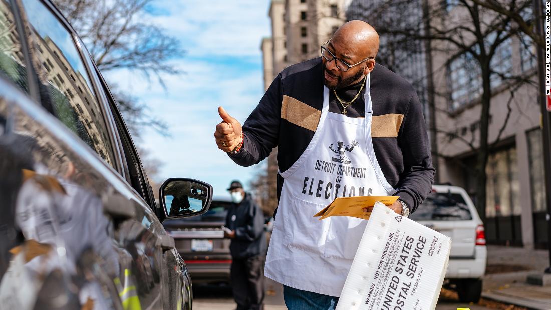 An election worker collects an absentee ballot from a car in Detroit on November 6.