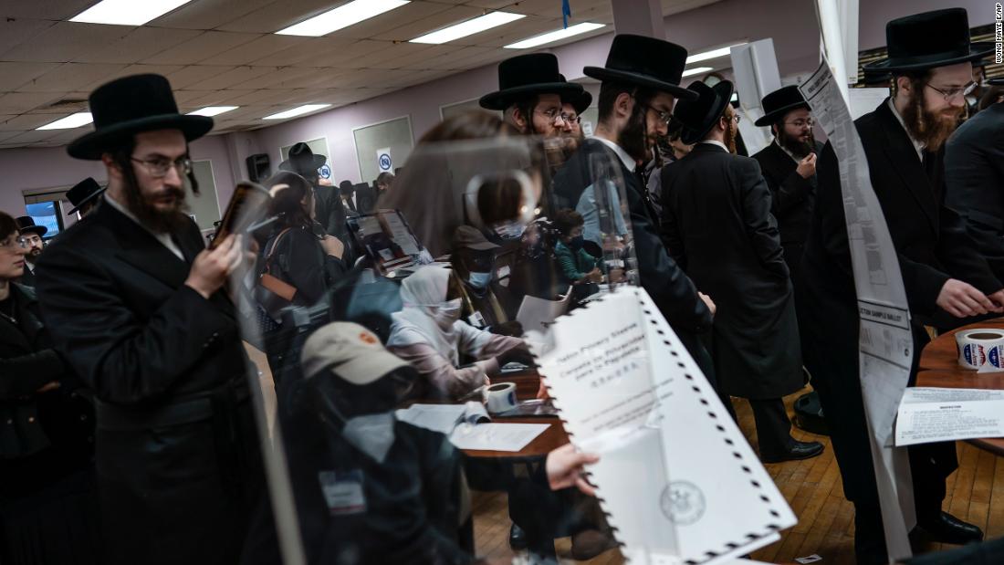 Poll workers are reflected by a piece of glass as people collect their ballot papers in Brooklyn, New York.
