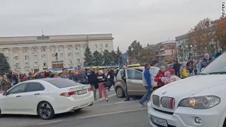 Crowd cheer and chant as they surround a car with Ukrainian soldiers in Kherson&#39;s main square on Friday. 