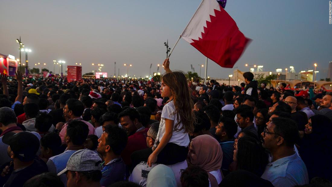 A girl waves a Qatari flag at a fan zone in Doha.