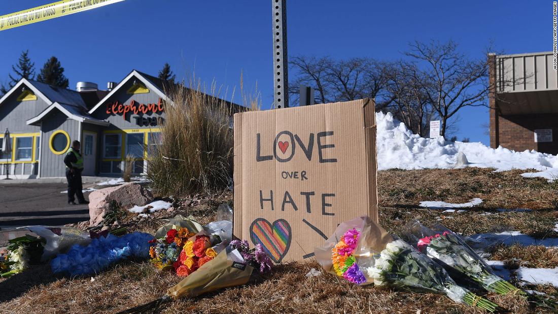 Bouquets of flowers and a sign reading &quot;love over hate&quot; are left near Club Q on Sunday.