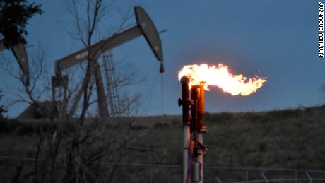A flare to burn methane from oil production is seen on a well pad near Watford City, North Dakota, Aug. 26, 2021. 