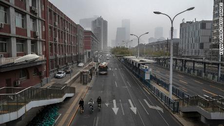 People ride bikes on an empty street near Beijing&#39;s central business district on November 24. 