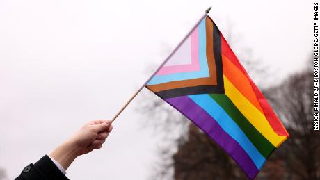 A person waves a Pride flag during a Transgender Day of Visibility Event named, We Are A State of Love: A Gathering of Visible Solidarity With LGBTQ Youth outside of the State House in Boston on March 31, 2022.