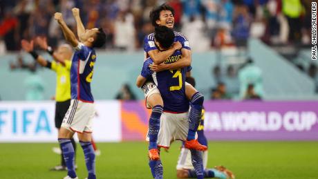 Japan players celebrate reaching the knockout stages after beating Spain.  