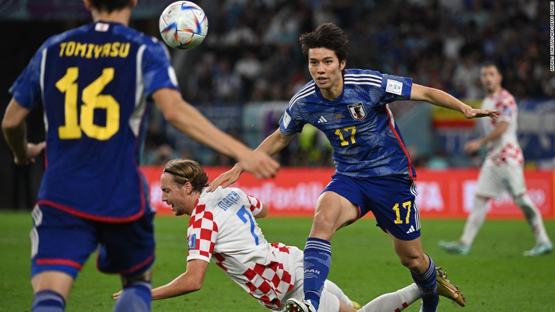 Croatian midfielder Lovro Majer falls near Japanese midfielder Ao Tanaka.